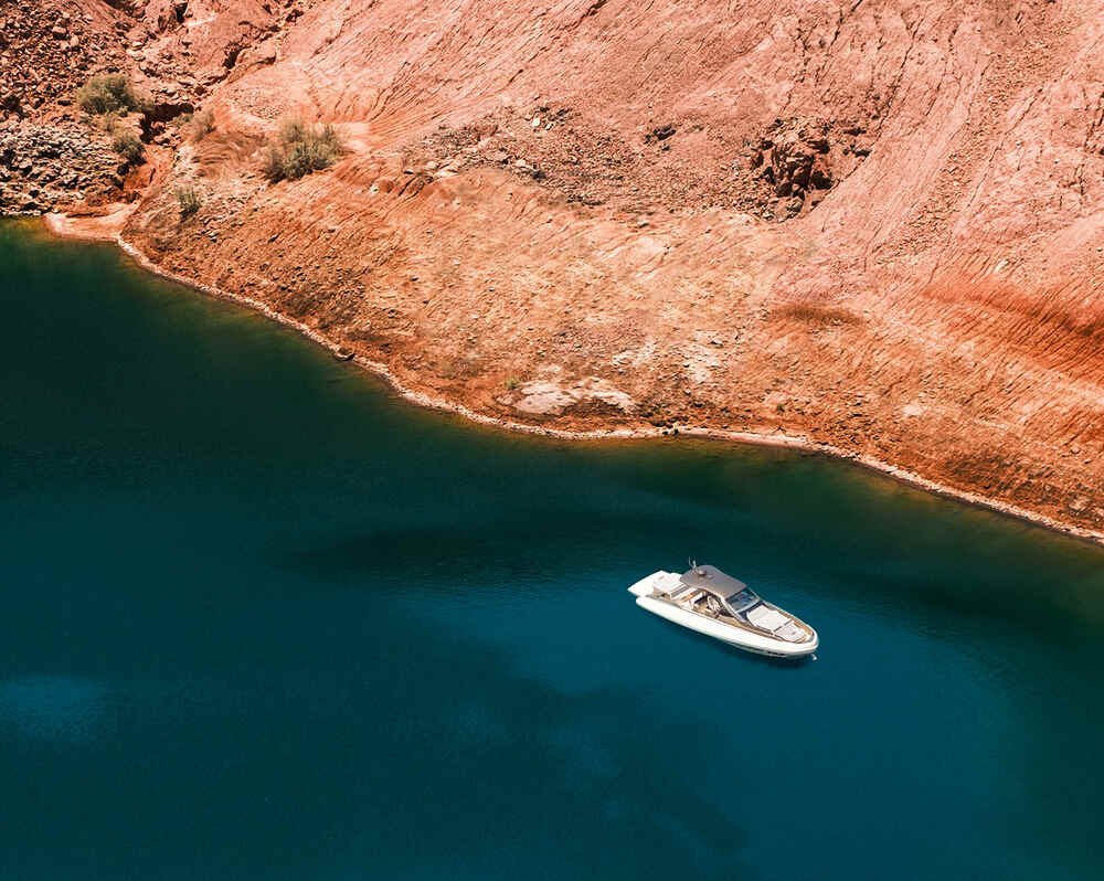 The Rebel 47 anchored on calm waters near a rugged coastline 